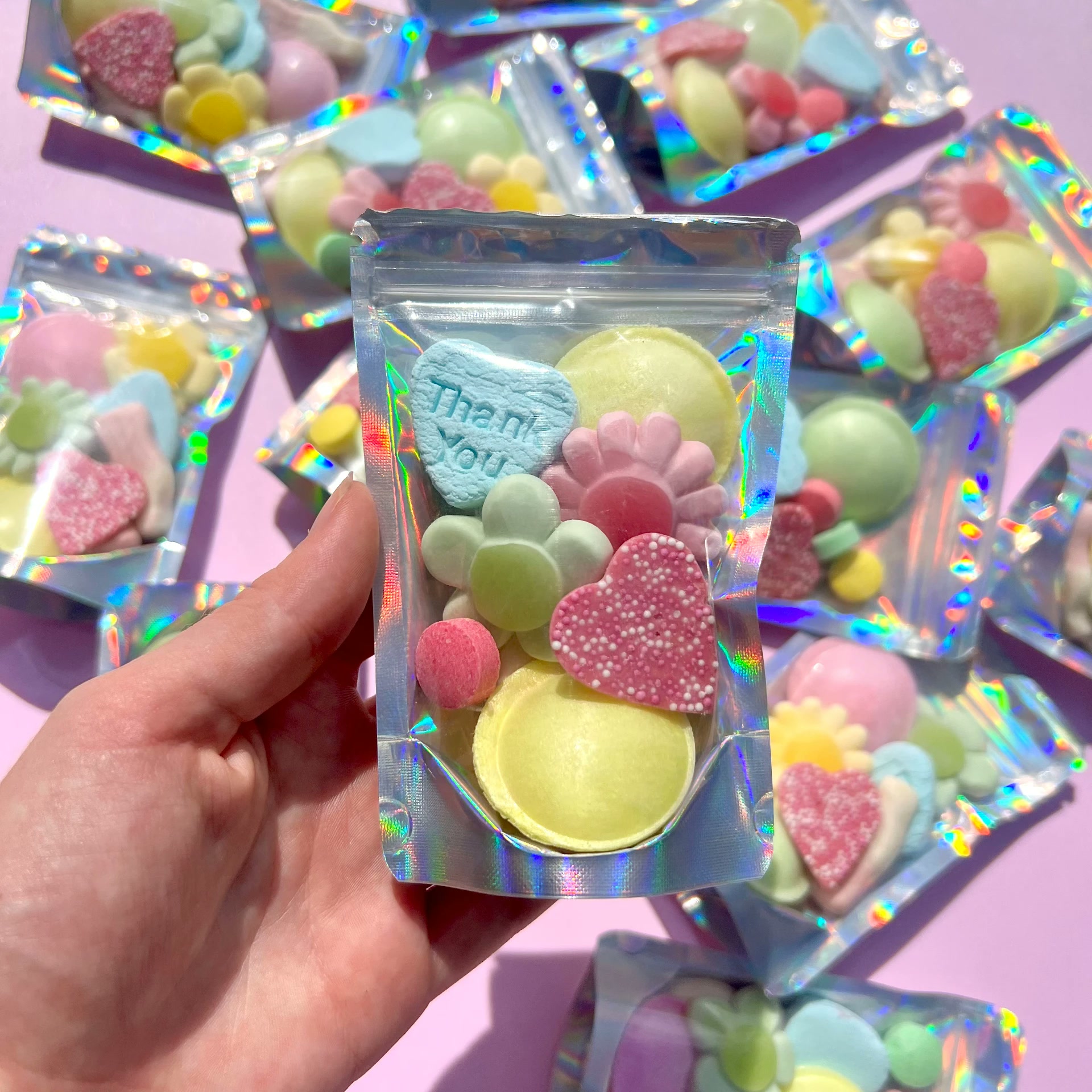 Hand holding a holographic favour bag filled with pastel candies including a 'Thank You' heart sweet